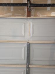 Garage door panel being in the process of being bent back into shape. We're looking at trying to get it back to about 90%.