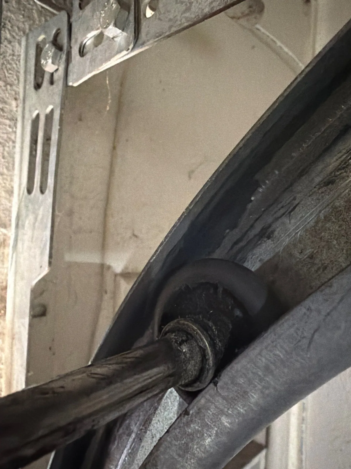 Chewed, worn garage door roller at the track hardware.