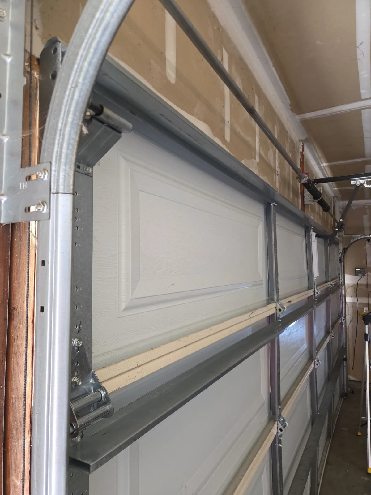 Two new reinforcement struts mounted across the repaired top garage door section.