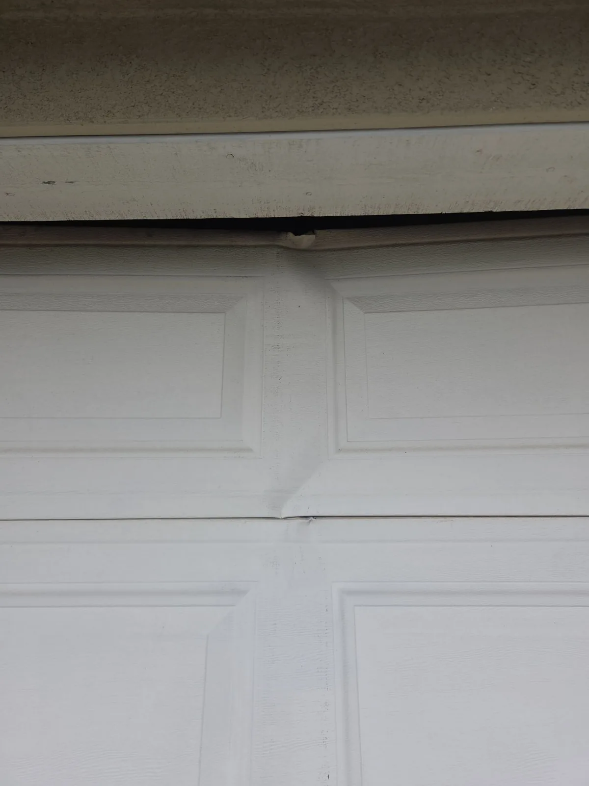 Damaged top section of a garage door before reinforcement.