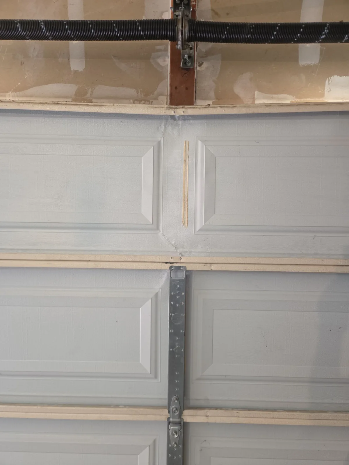 Car-damaged garage door panel being reshaped during repair.