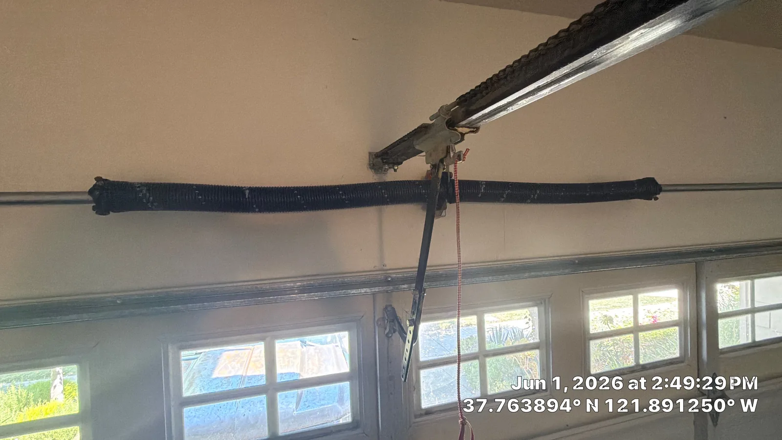 New powder-coated torsion spring hardware above the closed garage door.