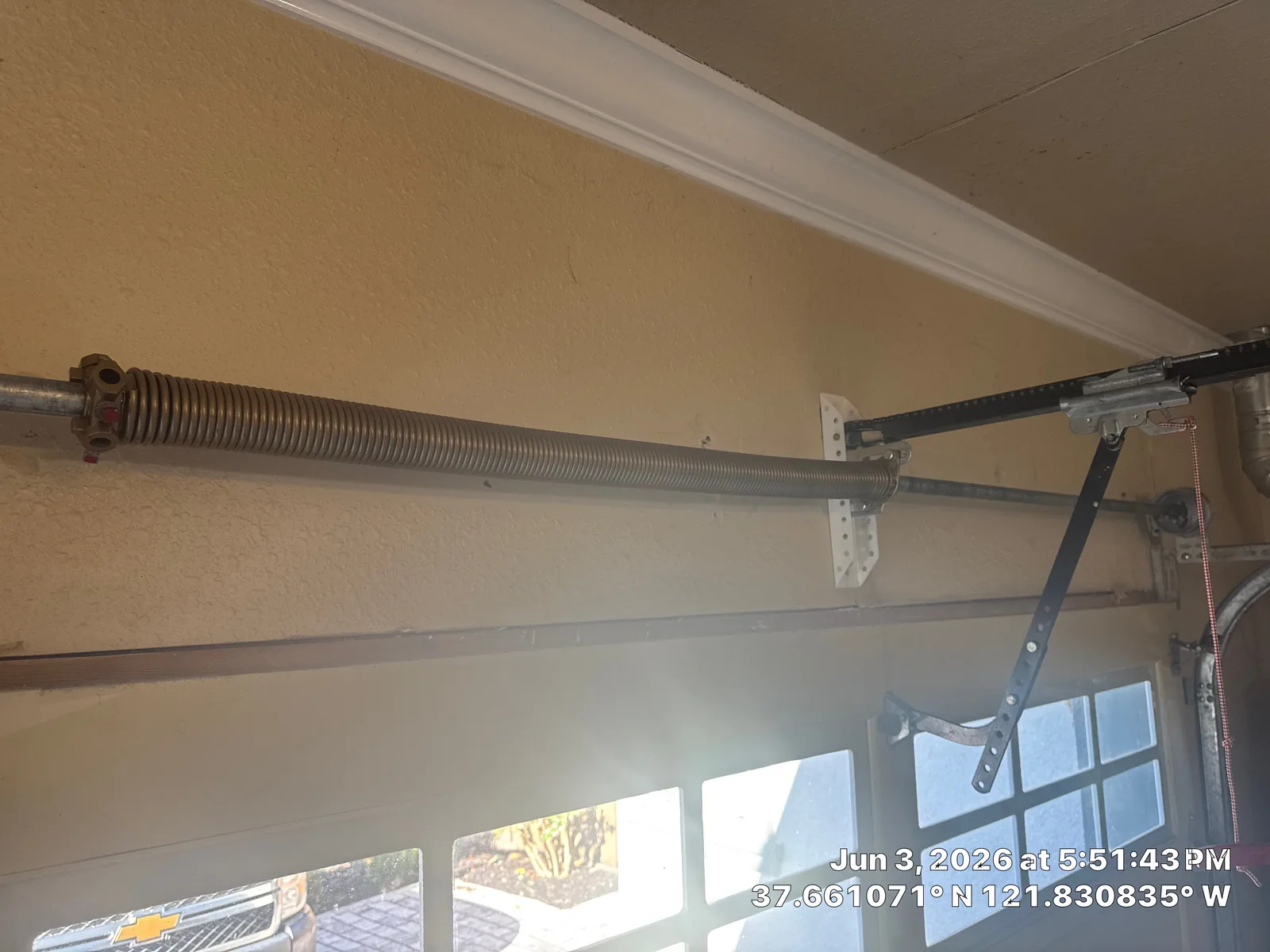 New powder-coated torsion spring installed above the garage door opening.