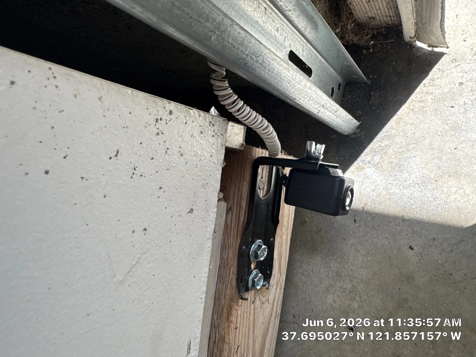 New garage door safety sensor positioned beside the lower track.
