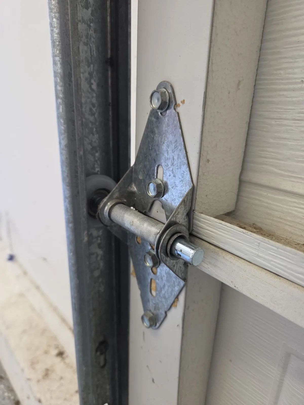 New nylon-coated garage door roller installed at the hinge and vertical track.