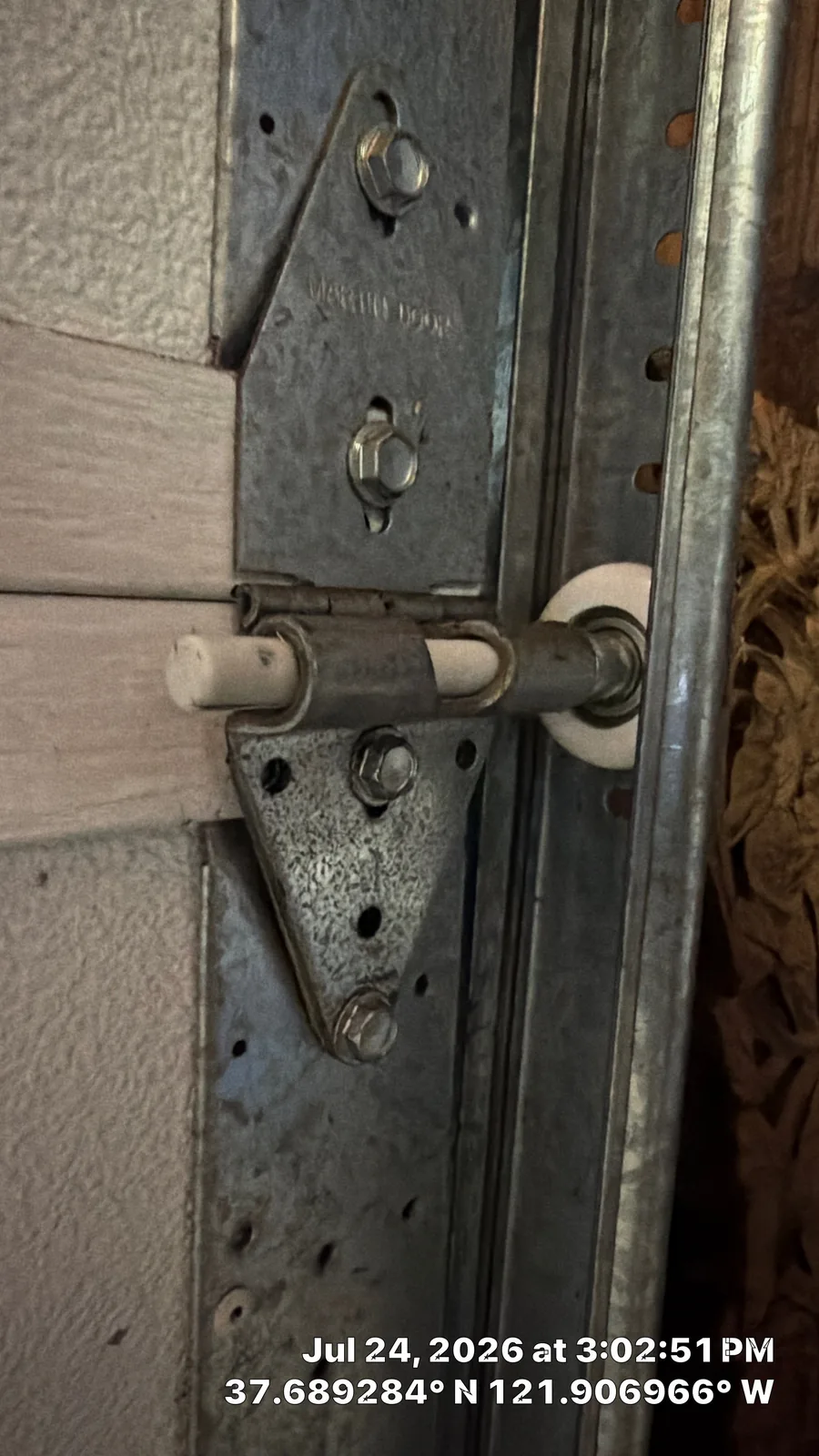 New coated-stem garage door roller installed at the hinge and vertical track.