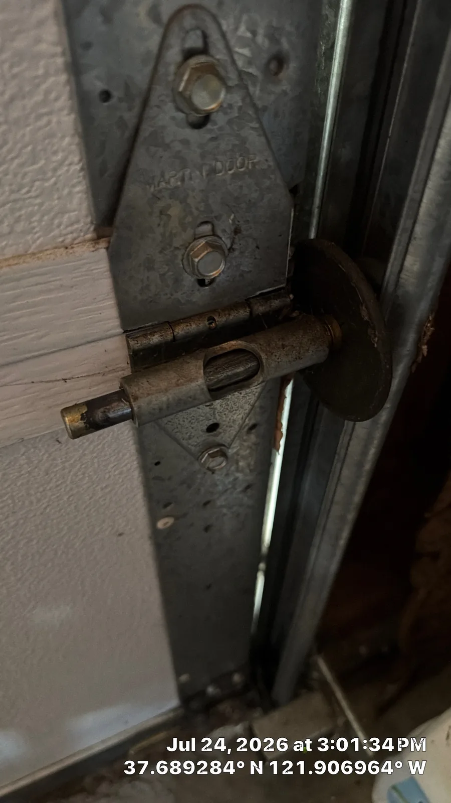 Older dust-covered garage door roller at the hinge and vertical track.