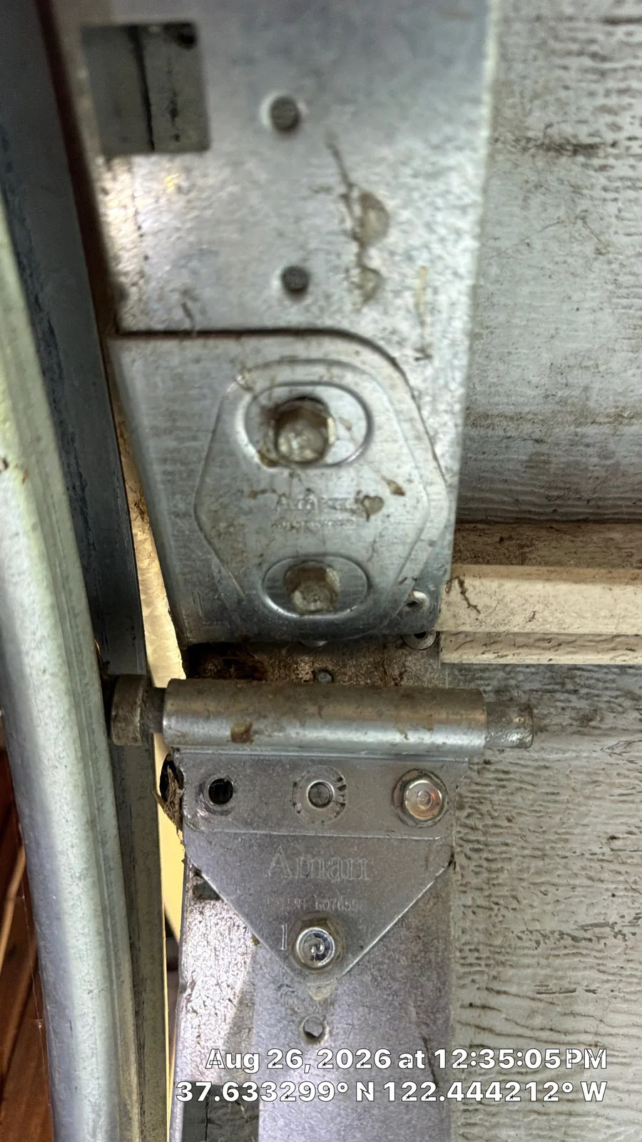 Detached hinge and roller-mount area on a San Bruno garage door section.