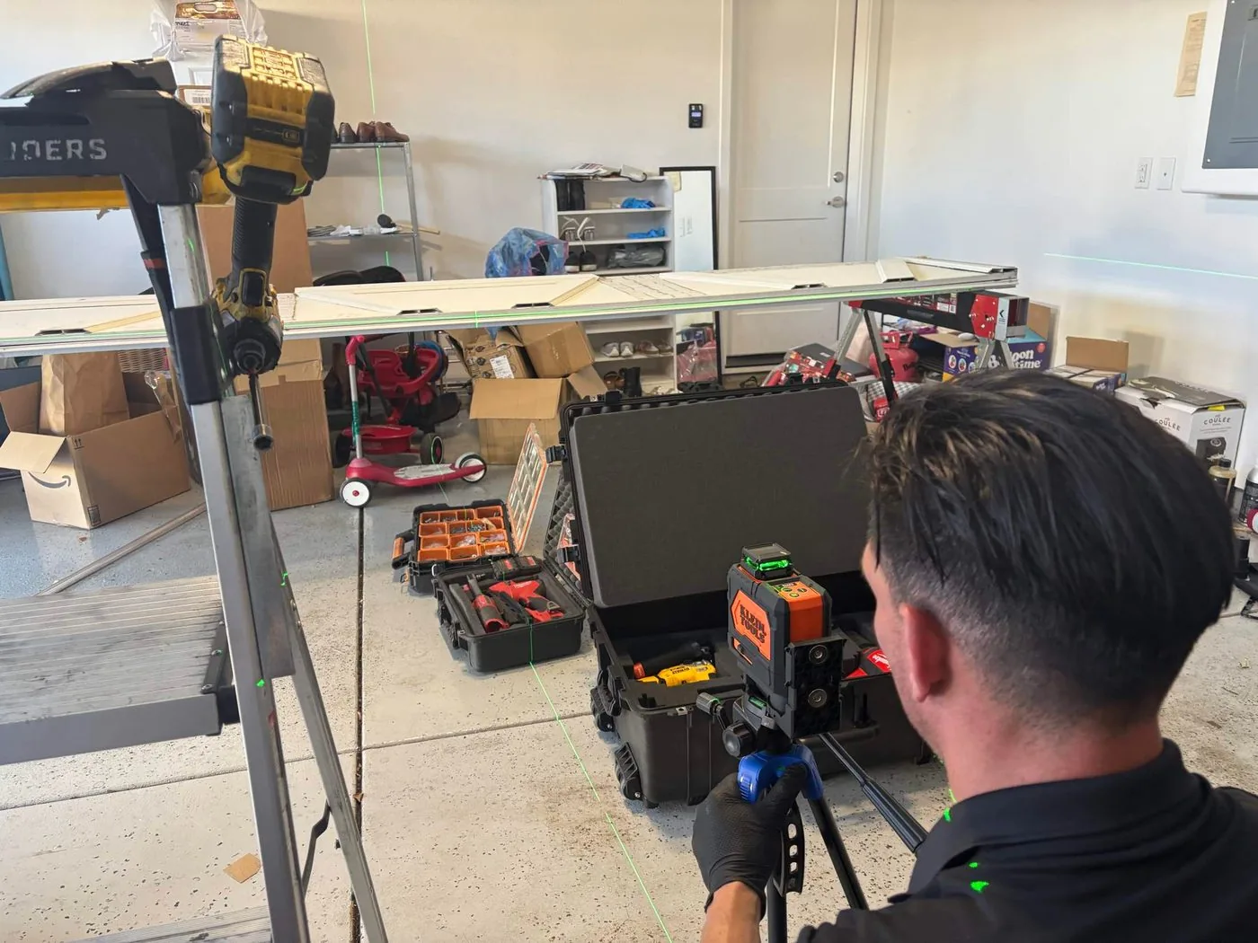 Valiant Garage Door technician using a Klein Tools green laser level to align a garage door panel in a Pleasanton garage