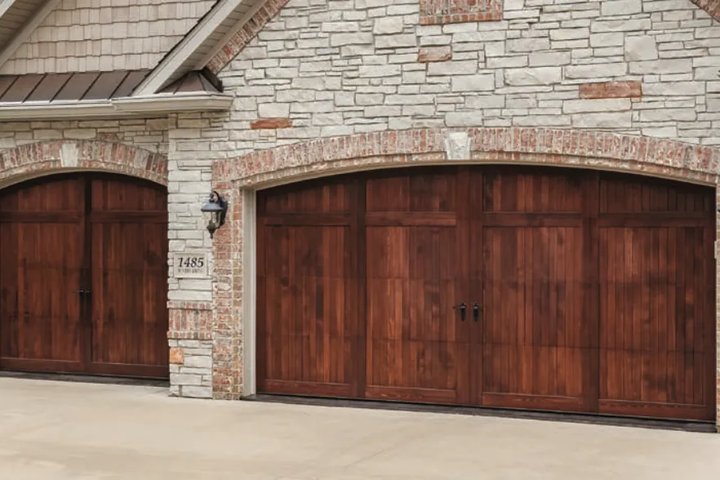 Carriage-style wood garage doors with stone and brick archway on a Pleasanton home