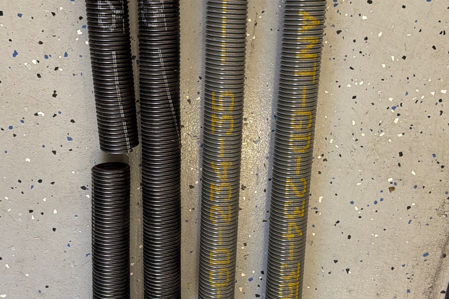 A snapped black garage door torsion spring beside new Valiant Door high-cycle replacement springs on a garage floor
