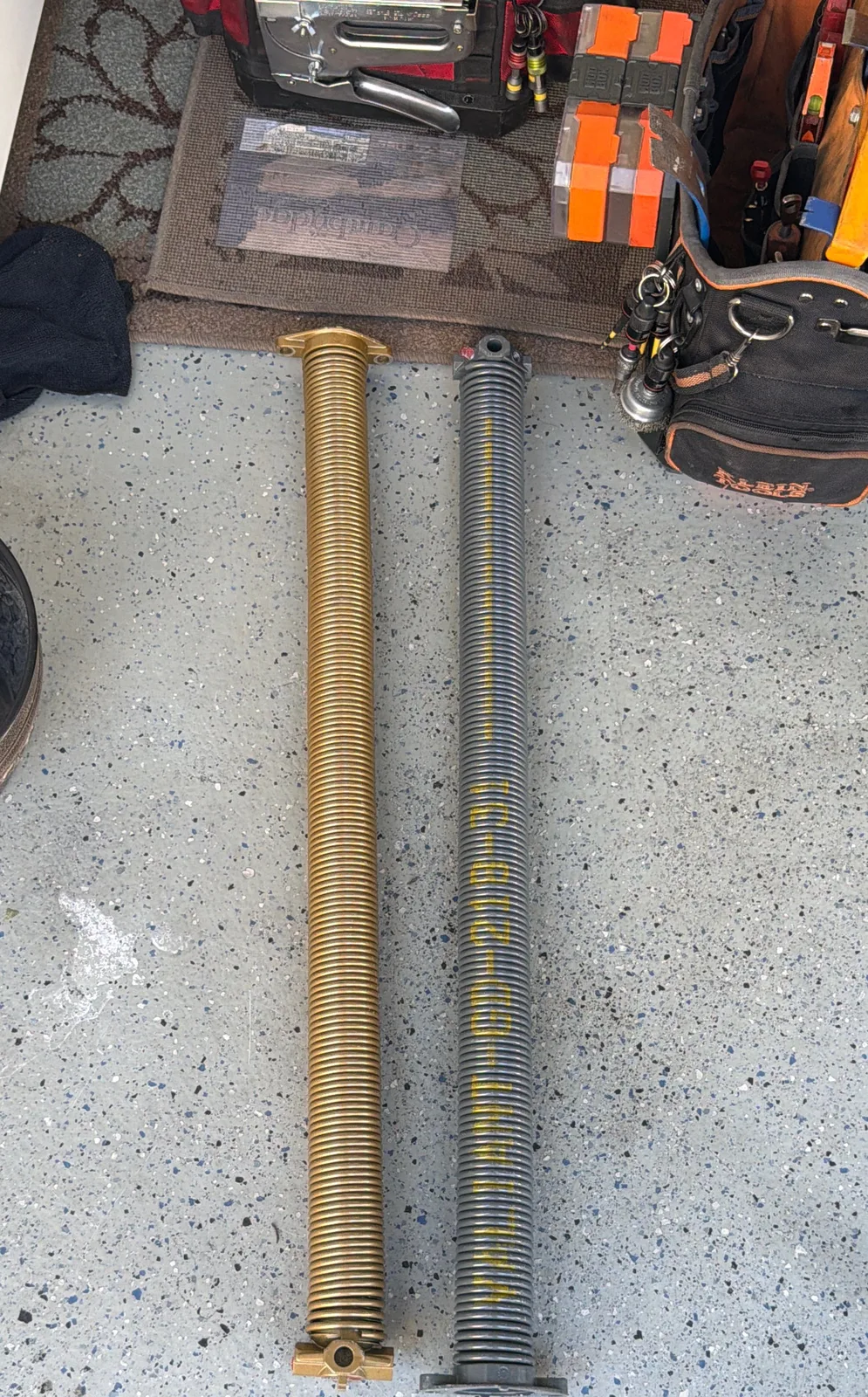 Wayne-Dalton TorqueMaster spring beside a new standard torsion spring after conversion